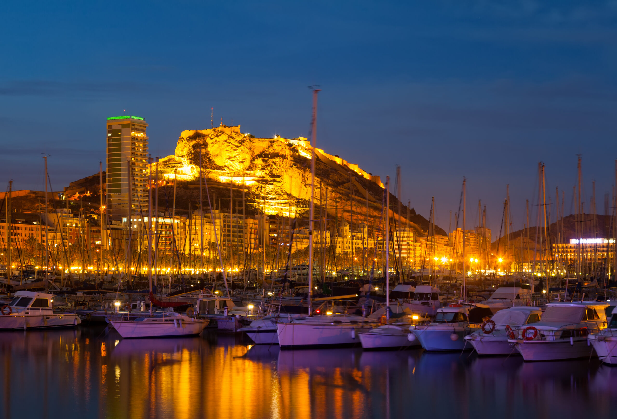 View of port with yachts against Castle of Santa Barbara in night. Alicante, Spain